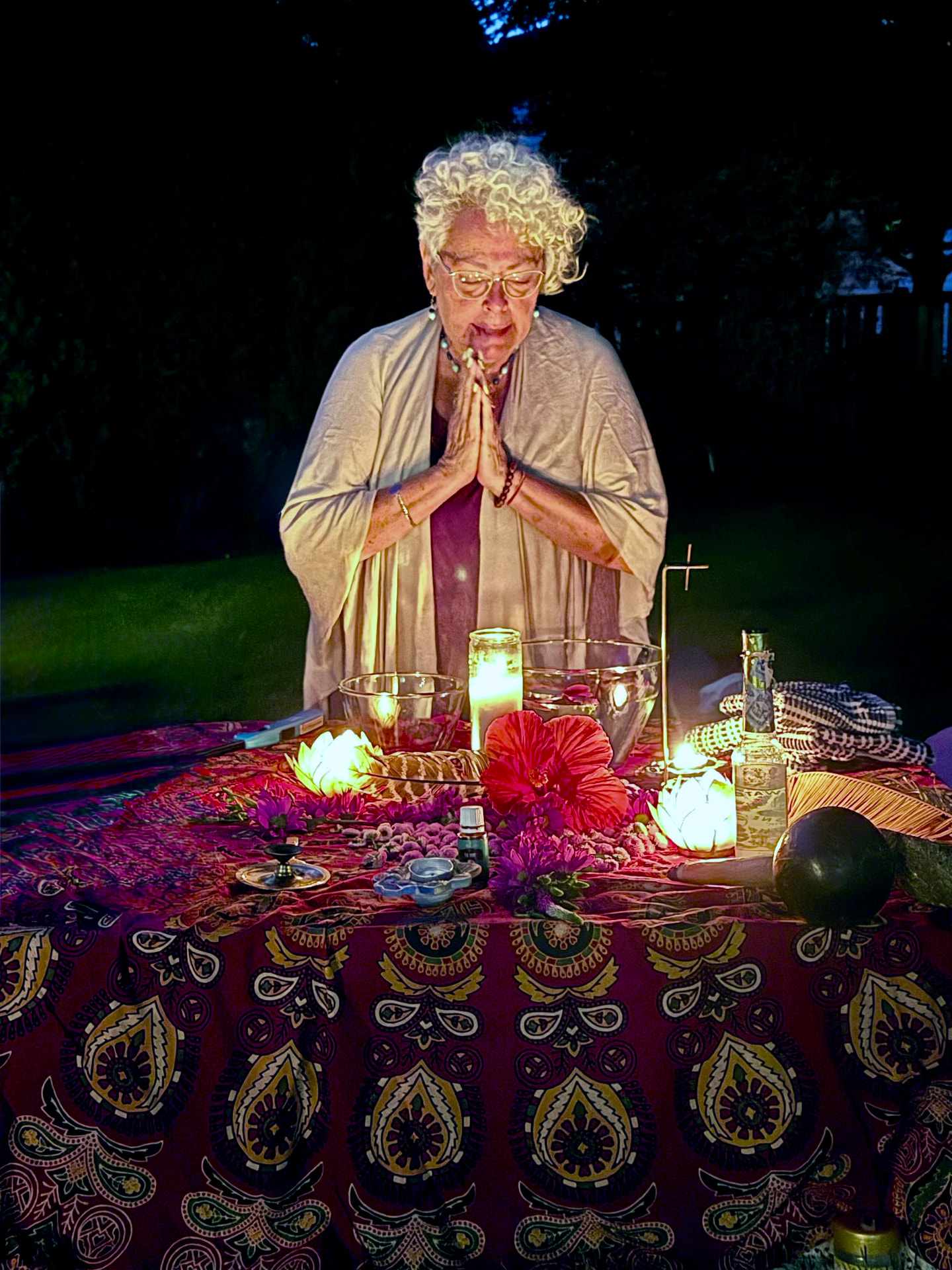 Yolanda Lozano in prayer at a candlelit altar with flowers
