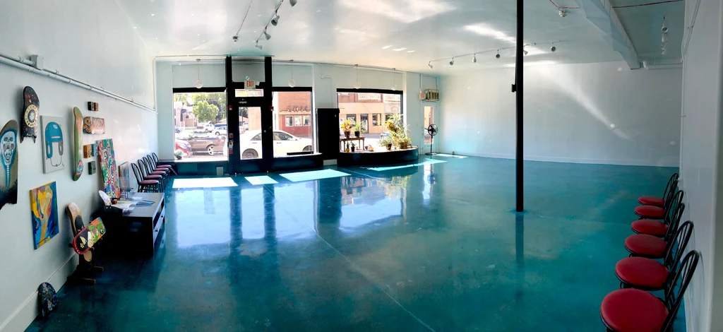 The Fargo Venue dance room: an open space with a polished teal floor, track lighting, big front windows and chairs along the walls