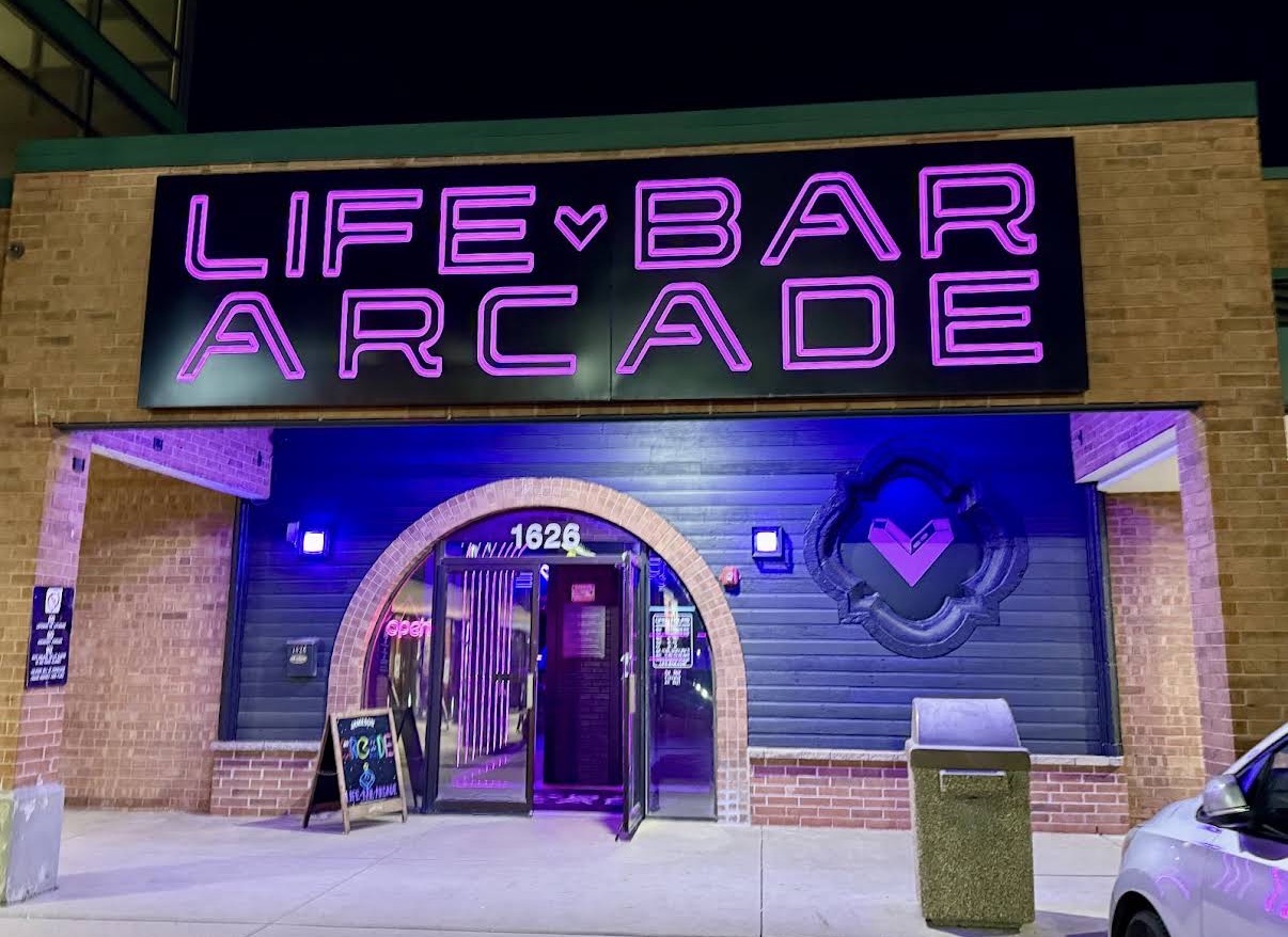 The neon Life Bar Arcade sign glowing pink above the entrance at night