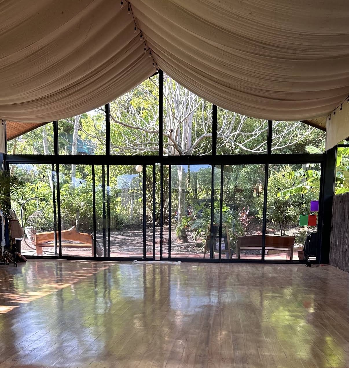 The dance floor in daylight, tall glass walls looking into the trees