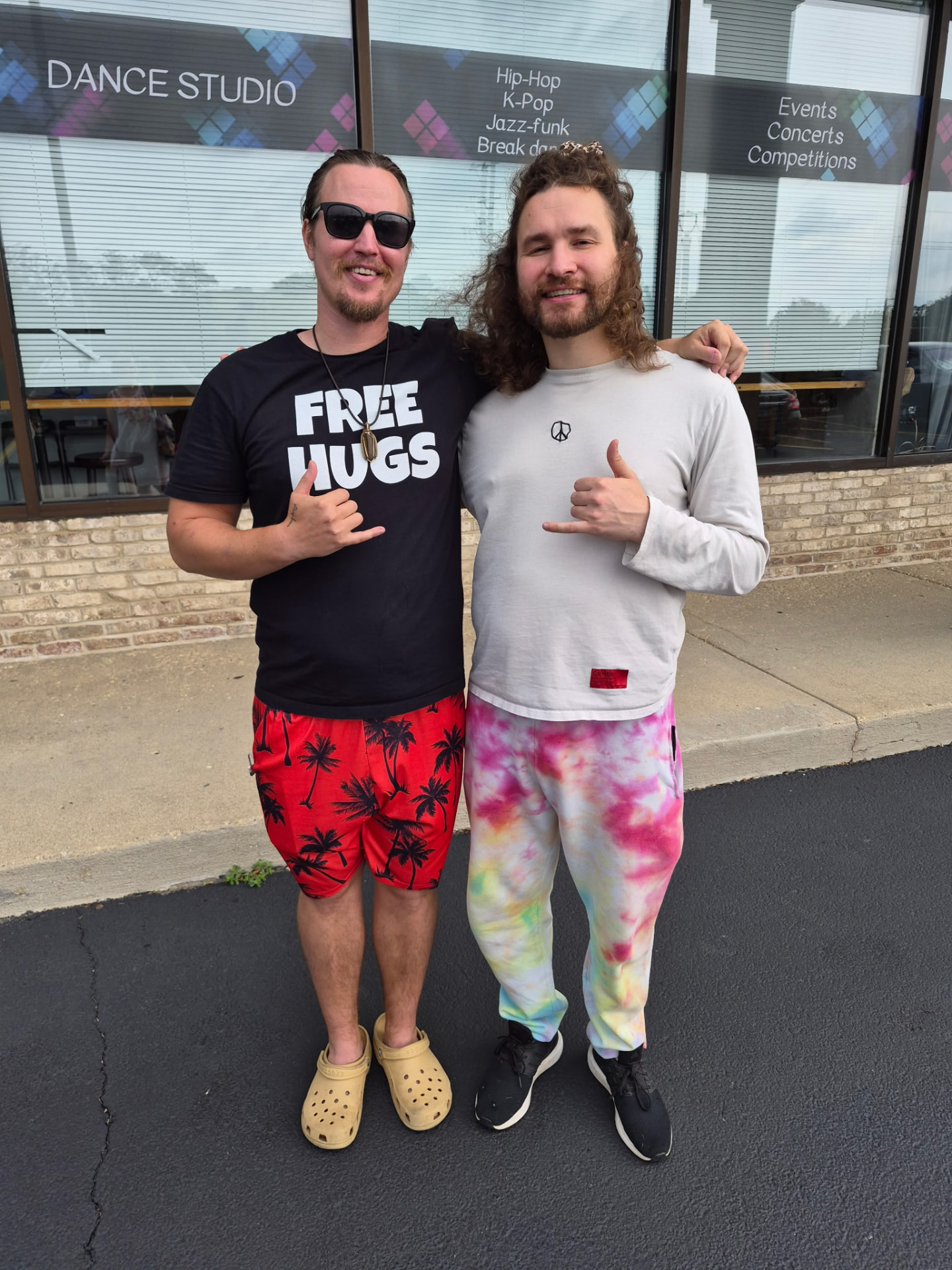 Kai and David giving shaka signs outside a dance studio