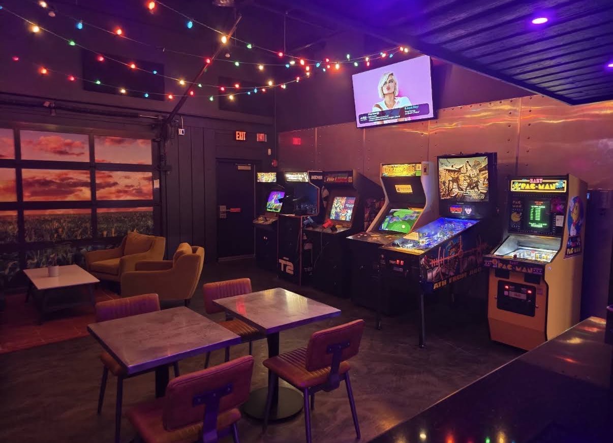 The back room at Life Bar Arcade with string lights, seating and arcade cabinets