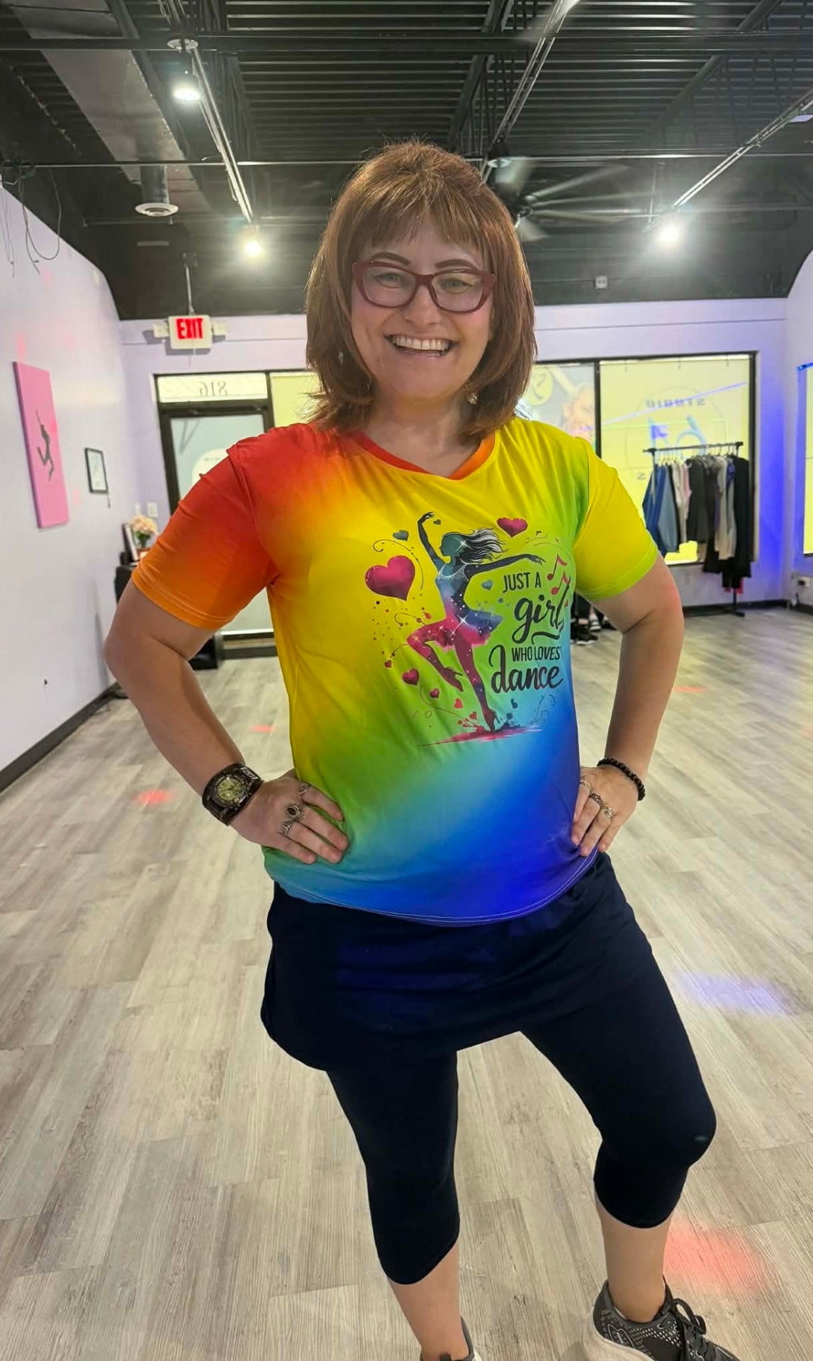 Vilija smiling in a rainbow 'Just a girl who loves dance' shirt in a dance studio