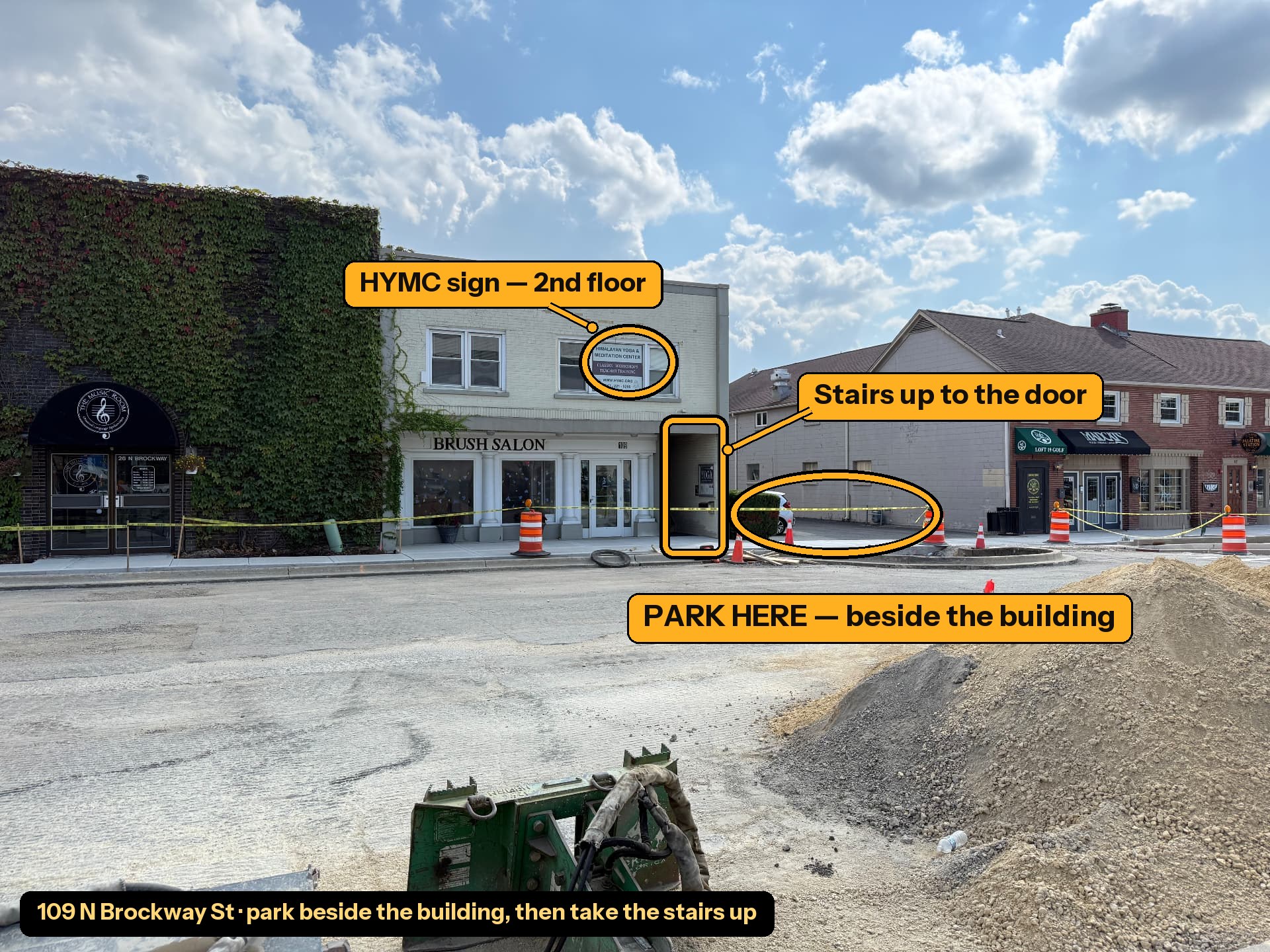 Annotated photo of the Himalayan Yoga and Meditation Center building showing where to park beside the building, the HYMC sign on the second floor, and the stairway opening on the right side of the building.